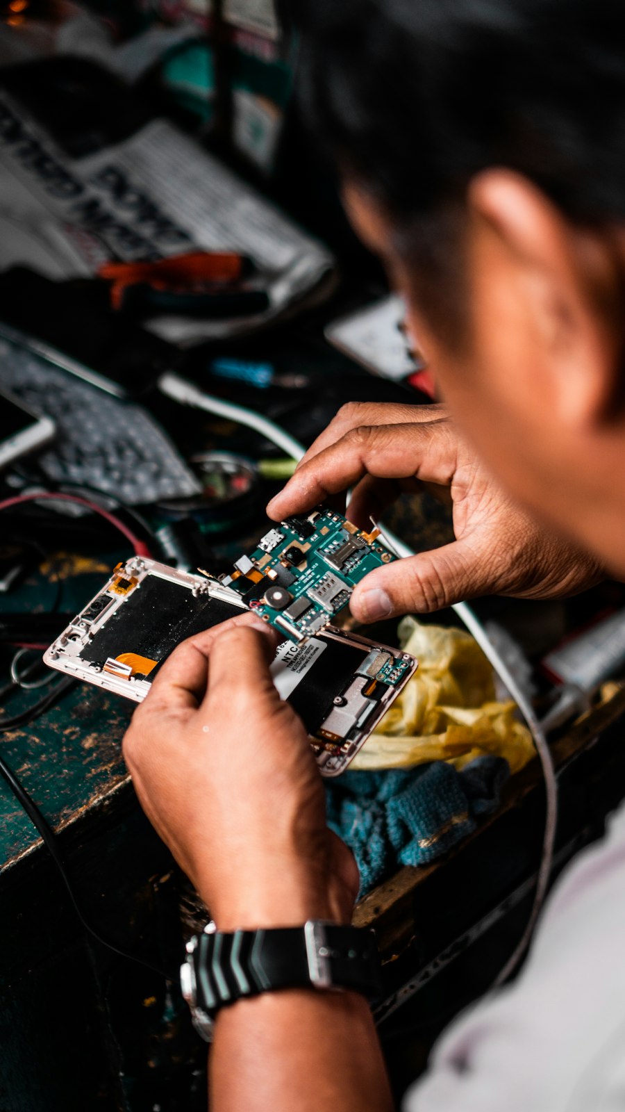 Close-up of a technician repairing a phone's circuit board