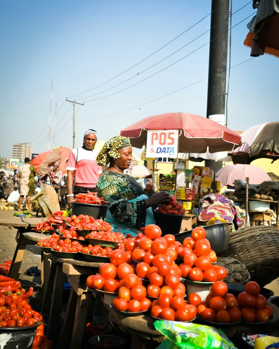 A provisions trader arranging tomatoes and peppers at her stall